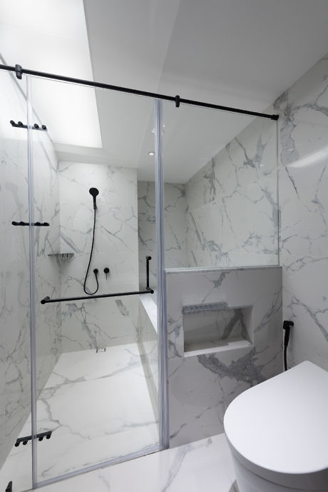 Modern bathroom with marble walls and glass shower enclosure.