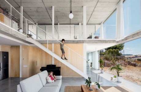 Contemporary home interior with exposed concrete and open staircase design.