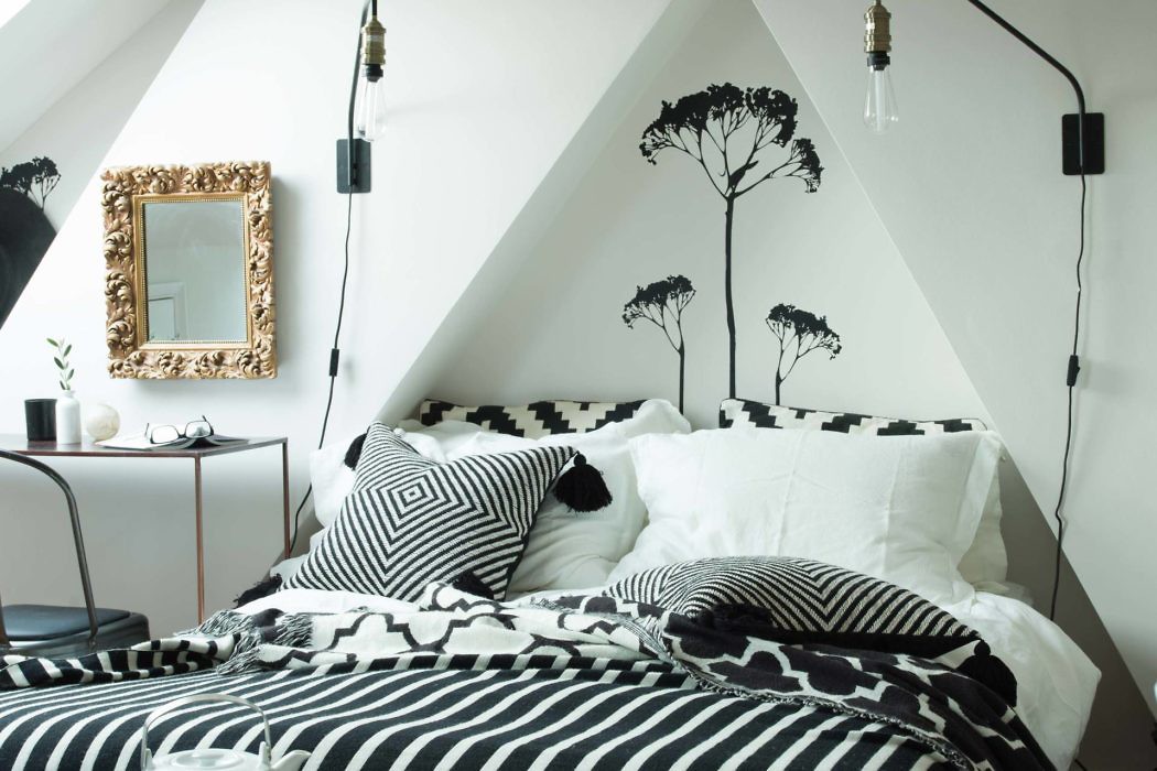 Attic bedroom with monochrome decor and tree wall mural.