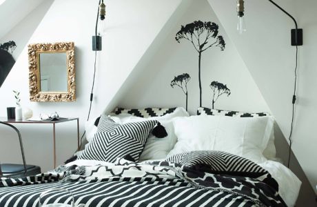 Attic bedroom with monochrome decor and tree wall mural.