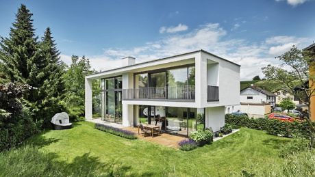 Contemporary white two-story home with large windows and a balcony.