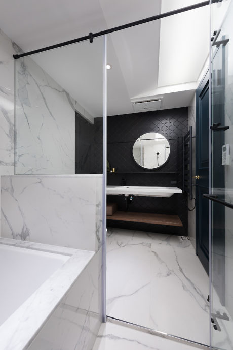 Contemporary bathroom with marble tiles and glass shower.