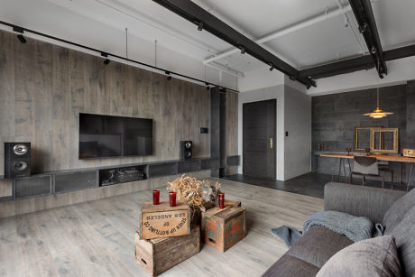 Modern living room with gray tones, wooden accents, and industrial ceiling.