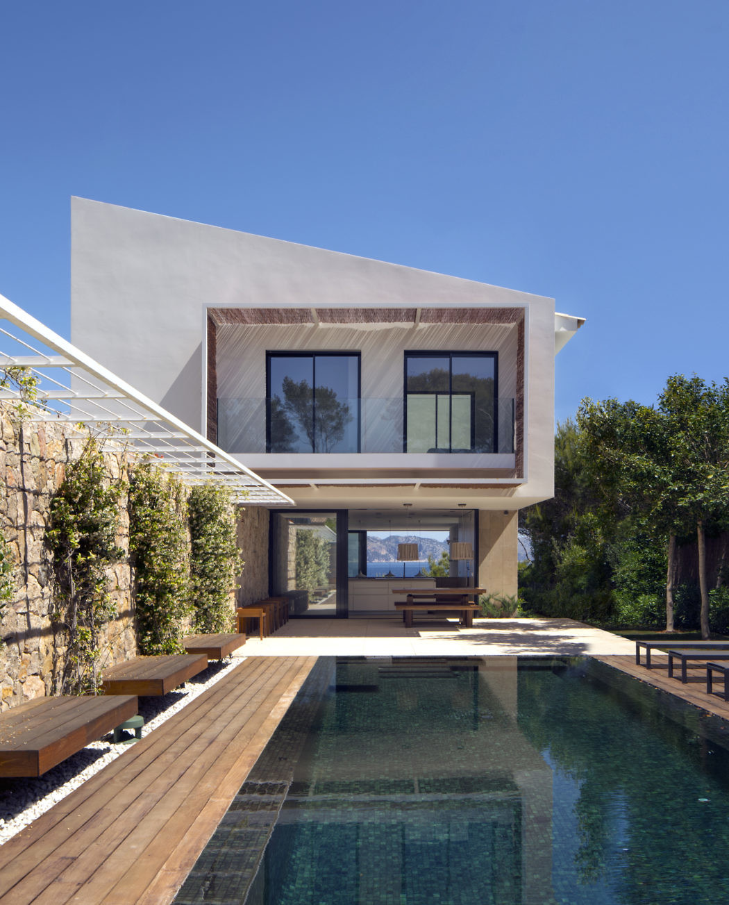 Modern home with large windows overlooking a swimming pool.