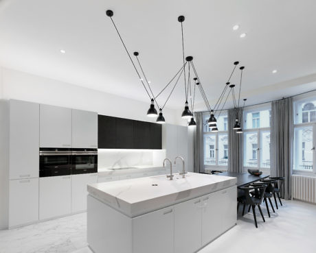 Modern kitchen with white cabinets, marble island, and pendant lights.