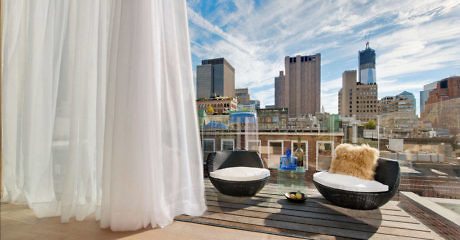 Urban rooftop patio with stylish seating and city skyline view.