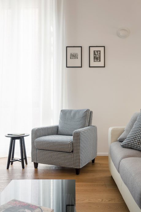 Minimalist living room with houndstooth armchair and sheer curtains.