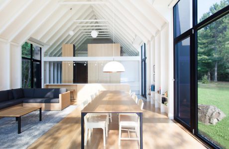 Modern open-plan living space with high ceilings, large windows, and wooden floors.