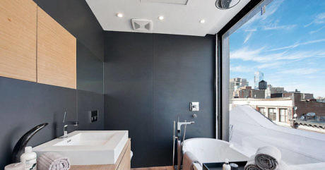 Modern bathroom with city view, bathtub, and dark walls.