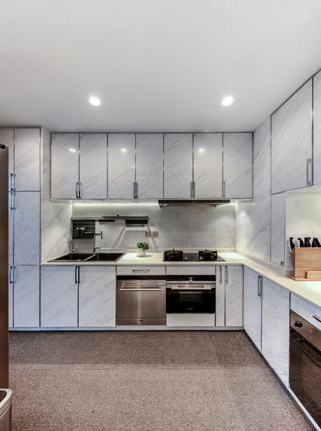Modern kitchen interior with gray cabinets and stainless steel appliances.