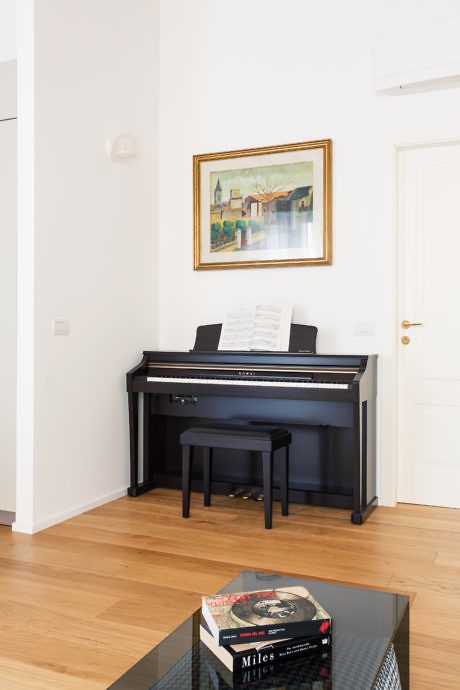 Elegant interior with a black piano, wooden flooring, and a framed artwork.