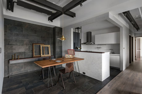 Contemporary kitchen with dark tiles, wooden table, and industrial elements.