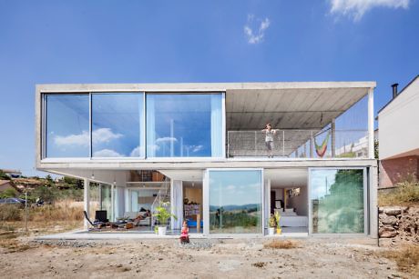 Modern two-story house with large glass windows and a child outside.