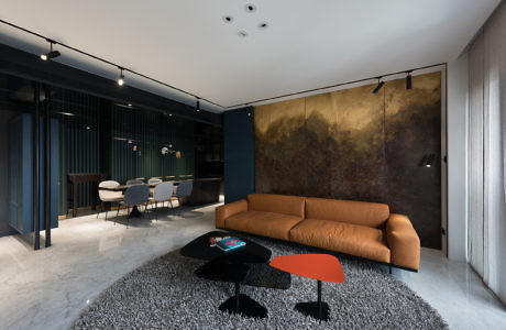 Modern living room with a tan sofa, black coffee table, and abstract art wall