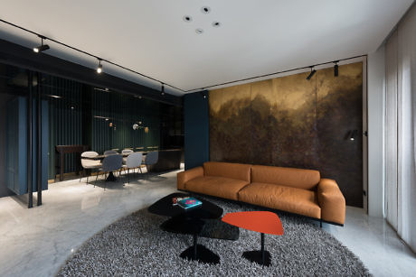 Modern living room with a tan sofa, black coffee table, and abstract art wall