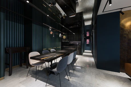 Contemporary dining area with sleek black furnishings and vertical green panels.