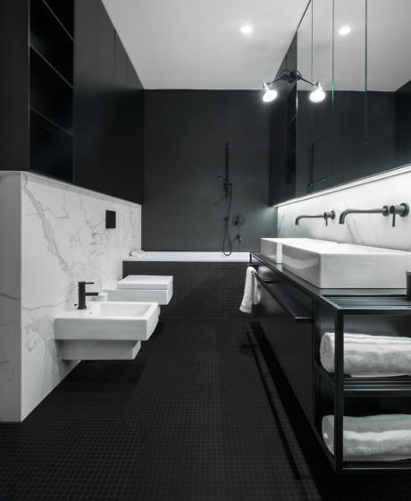 Modern bathroom with black walls, white marble accents, and dual sinks.