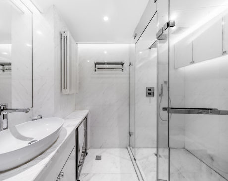 Sleek white marble bathroom with glass shower enclosure.