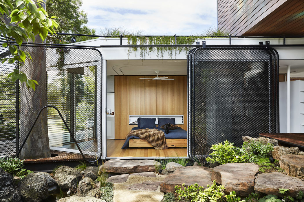 Modern bedroom with open mesh doors leading to a natural rock garden.