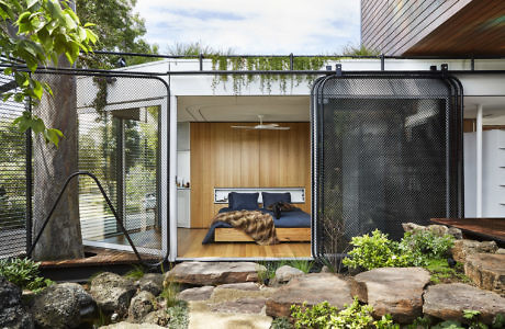 Modern bedroom with open mesh doors leading to a natural rock garden.