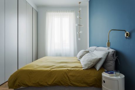 Contemporary bedroom with blue walls, a mustard bedspread, and minimalistic decor