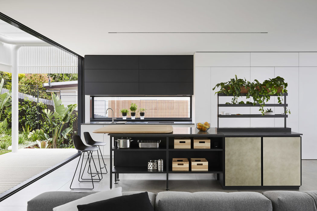 Modern kitchen with island, shelving plants, and view of garden.