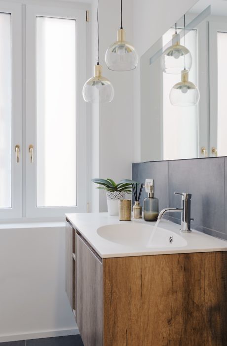 Modern bathroom with wooden vanity, pendant lights, and mirror.