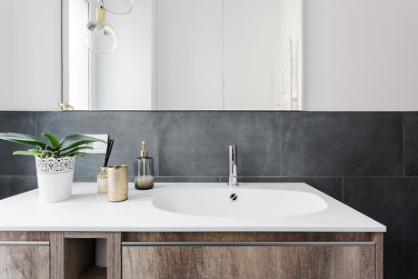 Contemporary bathroom with grey tiles and wooden vanity.