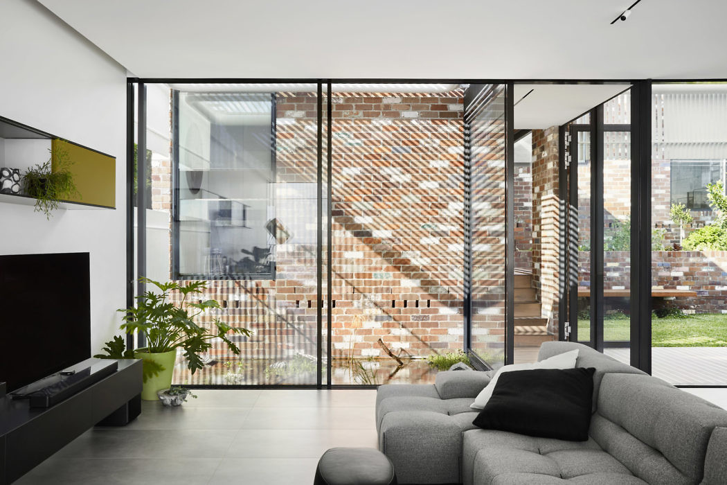 Contemporary living room with glass walls and brick accents.