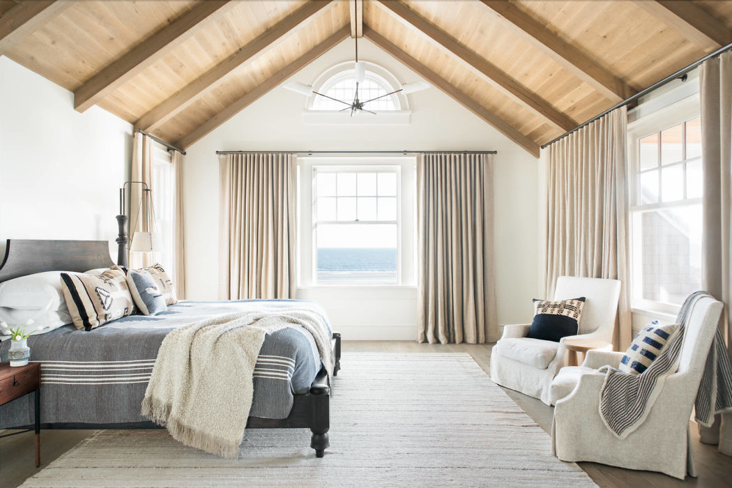 Coastal-style bedroom with exposed beams and ocean view.