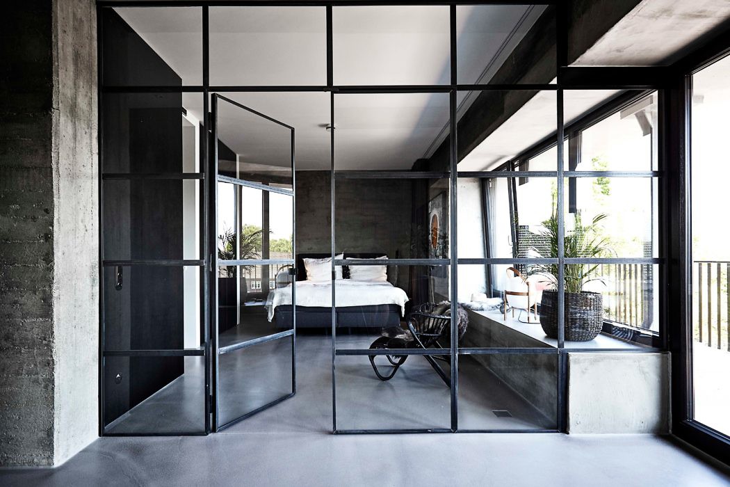 Modern bedroom with glass partition and concrete walls