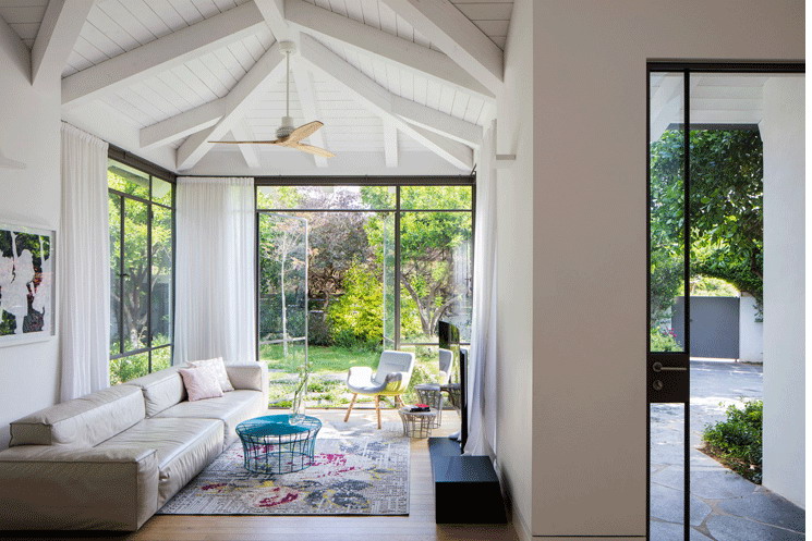 Bright living room with vaulted ceilings, large windows, and garden view.