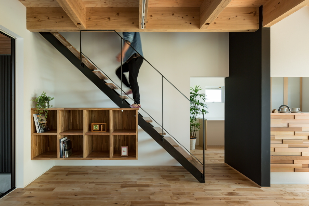 Contemporary interior with floating wooden staircase and bookshelf.