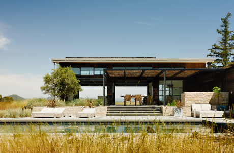 Contemporary house with large windows and a flat roof, overlooking a grassy field