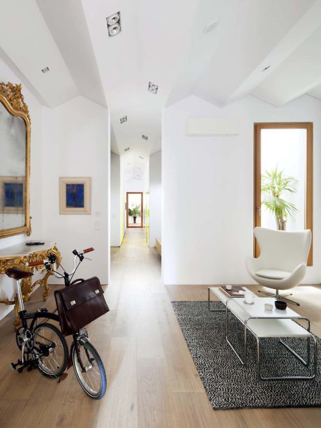 Contemporary hallway with white walls, wooden floors, and eclectic decor.
