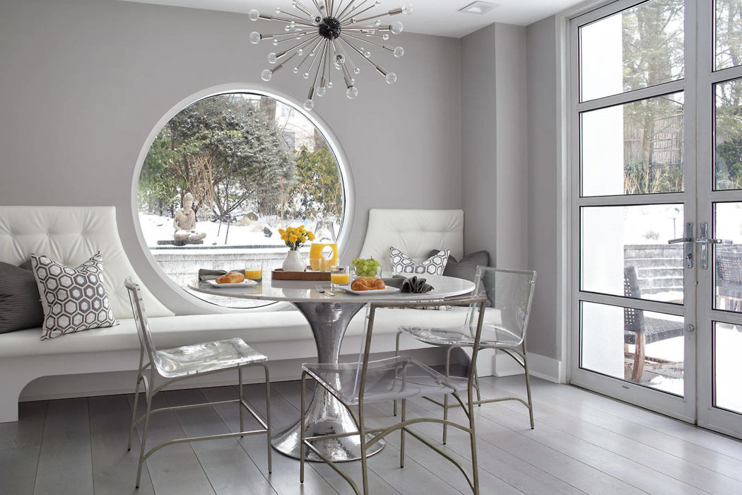 Minimalist breakfast nook with large round window and snow view.