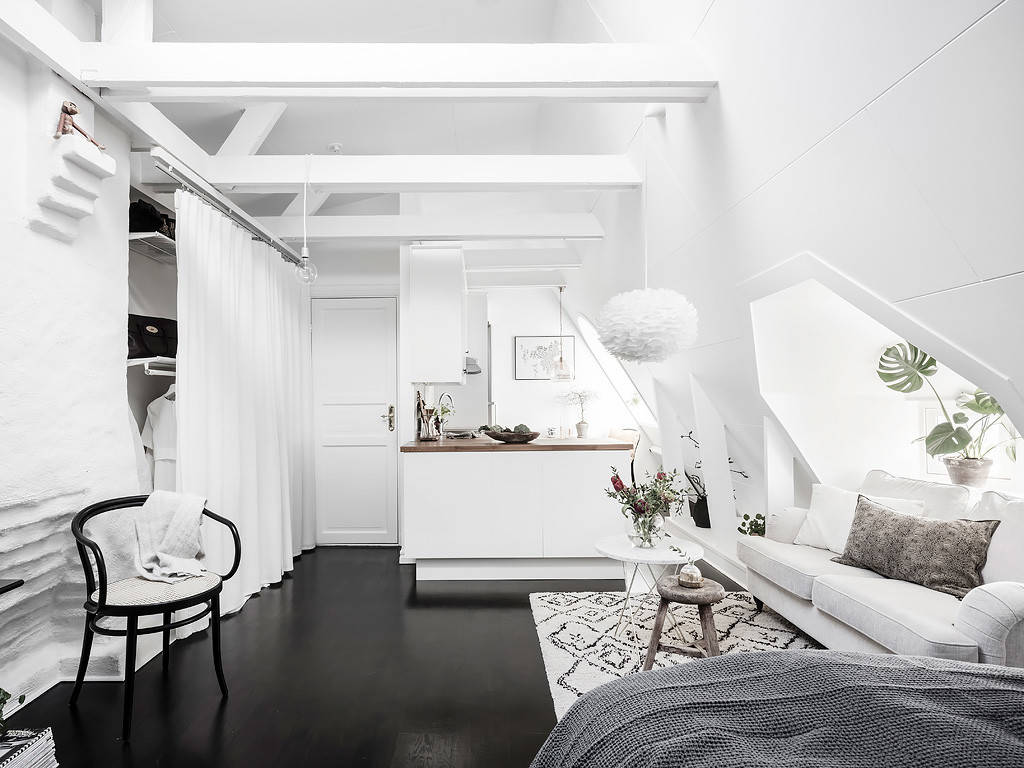 Sleek white loft space with contrasting black floor and exposed beams.