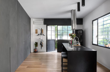 Modern kitchen with black island, stainless steel appliances, and hardwood floors.