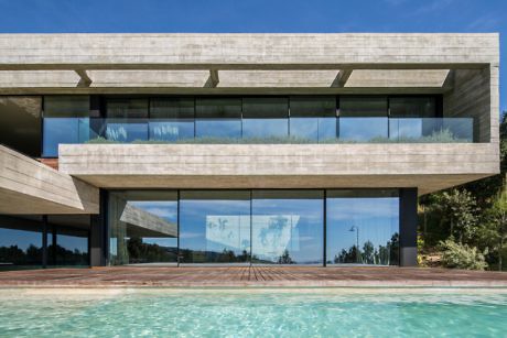 Contemporary house with large glass facade overlooking a pool.