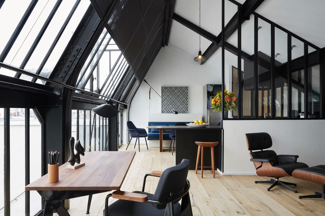 Chic attic office with black-framed windows and skylights.