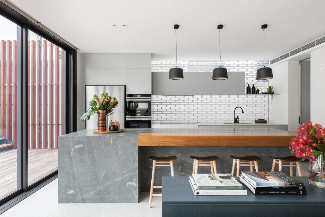Modern kitchen with island, bar stools, and pendant lights.