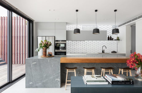 Modern kitchen with island, bar stools, and pendant lights.