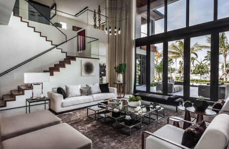 Modern living room with floating staircase and tropical view outside large windows.