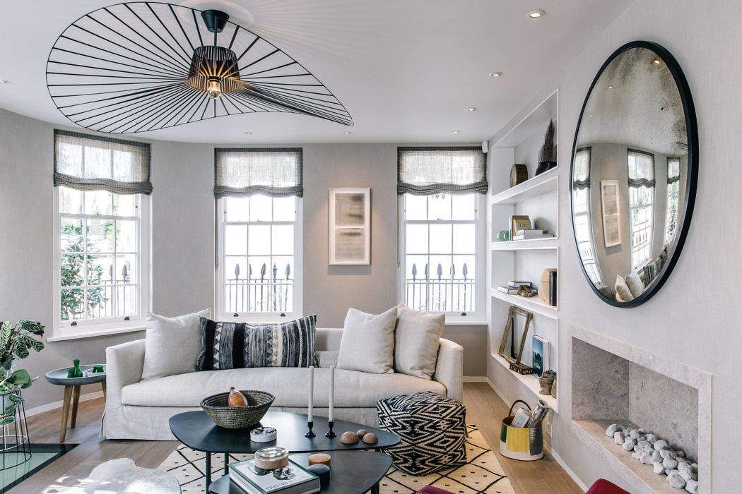 Elegant living room with white sofa, geometric rug, and distinctive oval mirror.