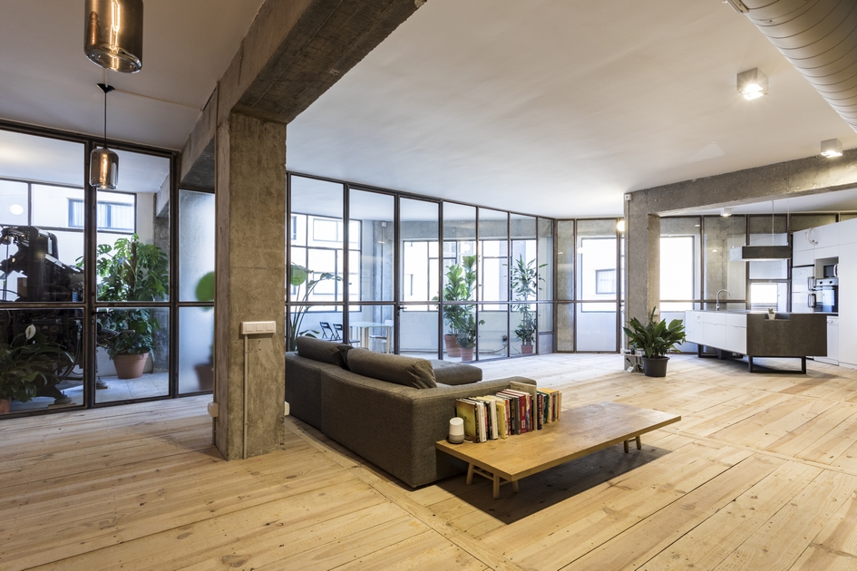 Modern interior with wooden floors, sectional sofa, and large windows.
