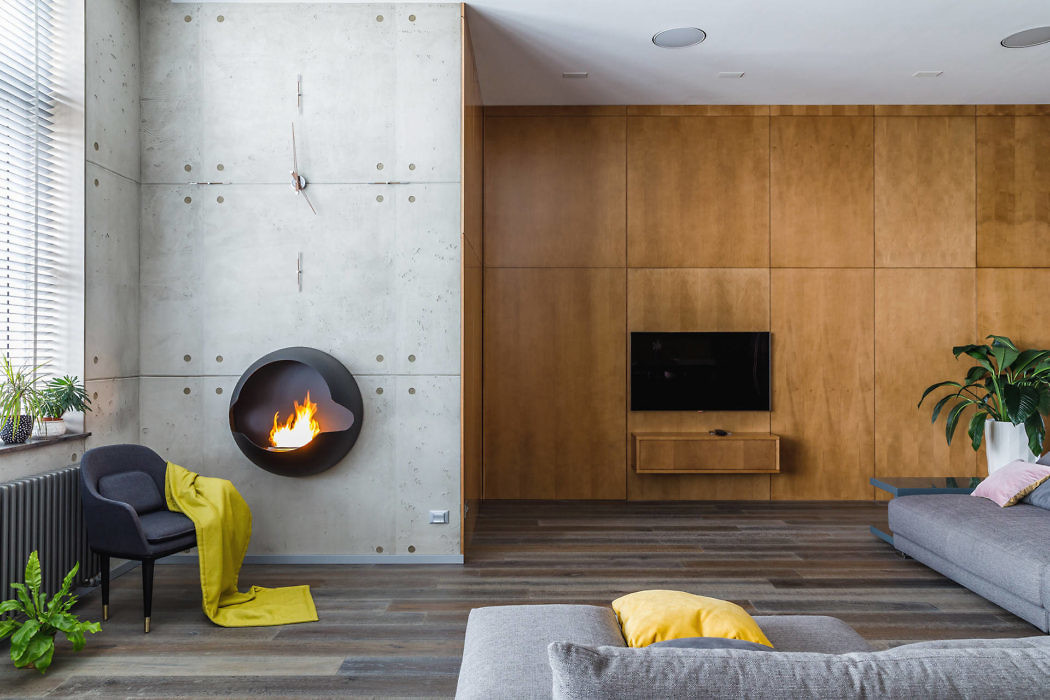 Modern living room with concrete and wood walls, floating fireplace, and minimalist decor.