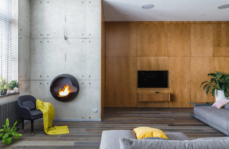 Modern living room with concrete and wood walls, floating fireplace, and minimalist decor.