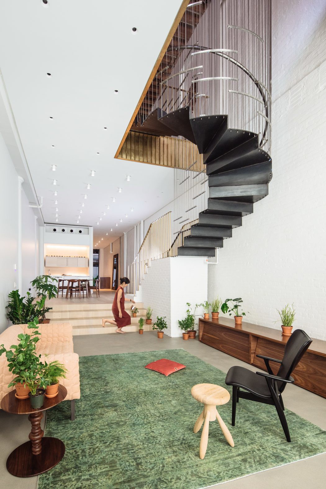 Modern interior with spiral staircase, seating area, and plants.