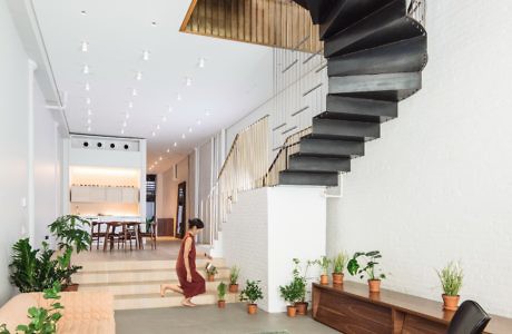 Modern interior with spiral staircase, seating area, and plants.