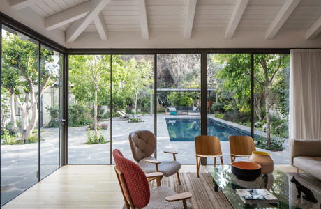 Modern living room with large windows overlooking a pool.